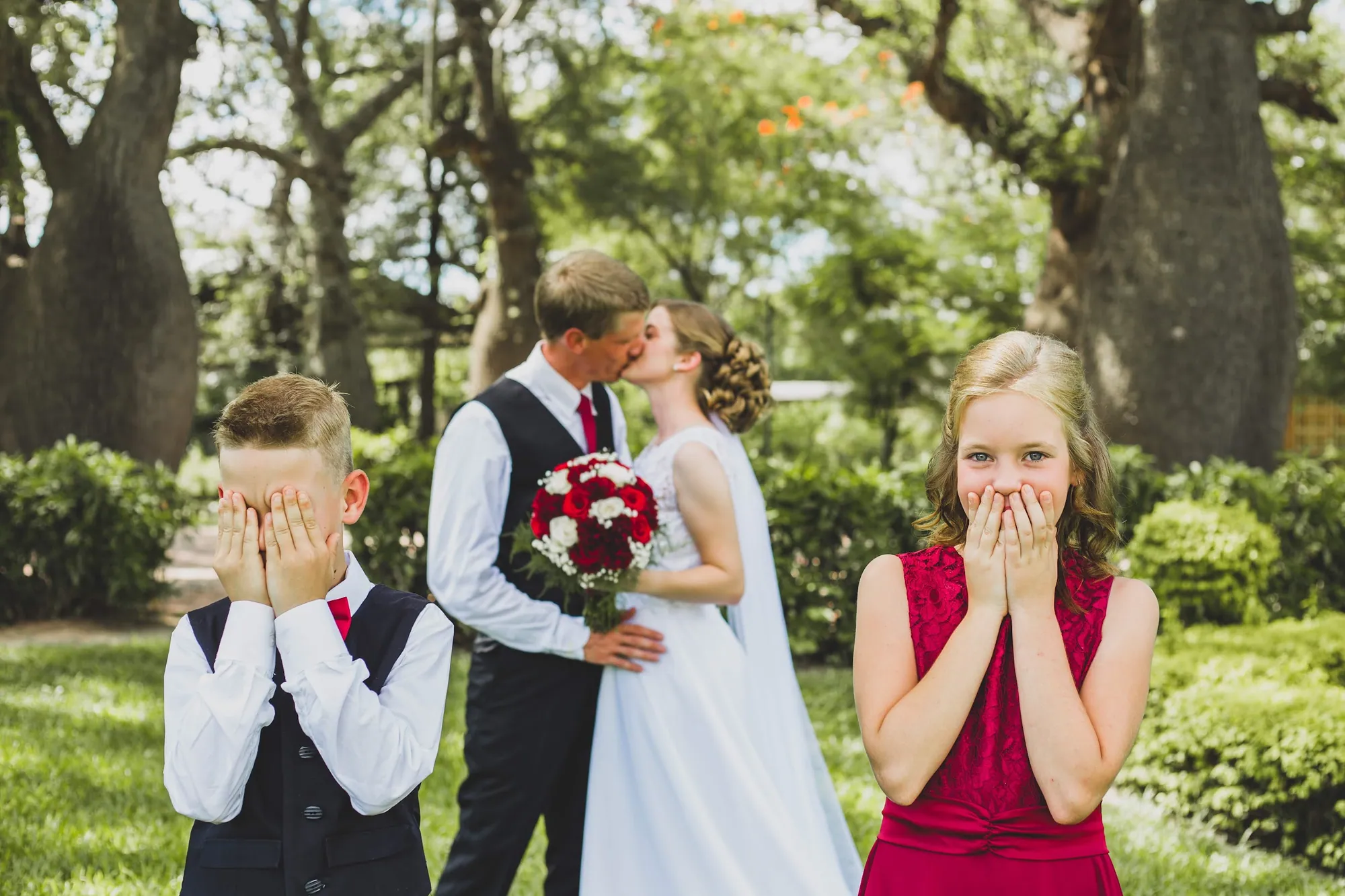 Los novios se besan mientras dos niños se tapan los ojos